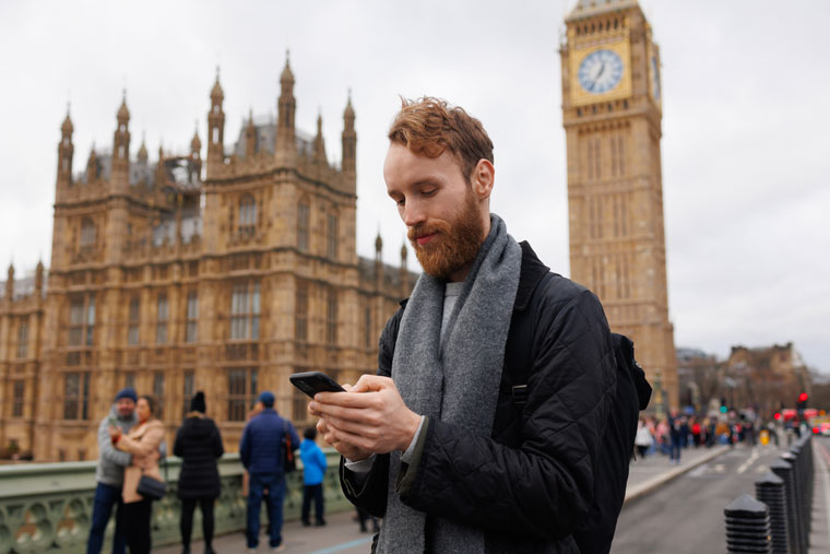 man on phone outside houses of parliament